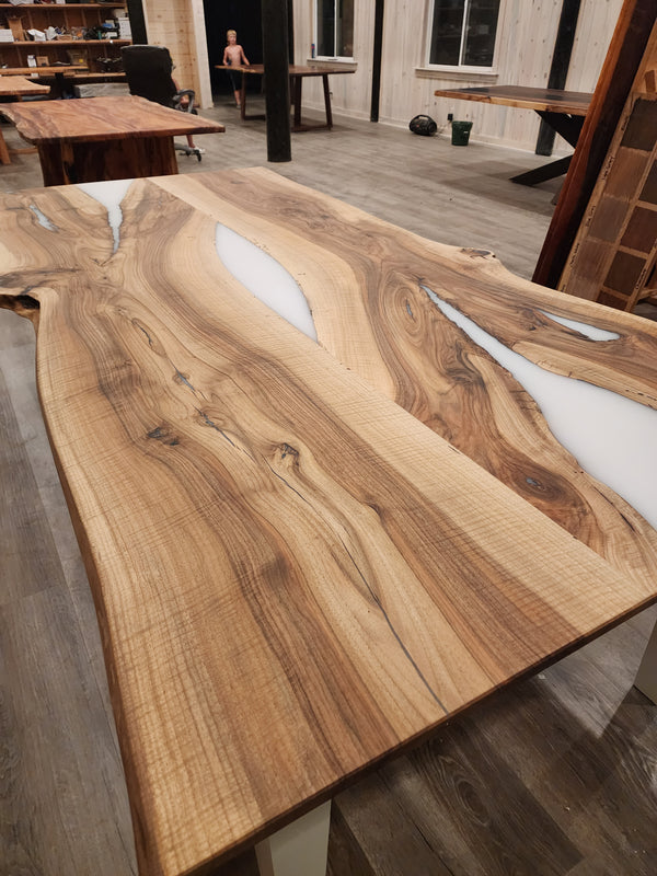 front view of english walnut wood dining table with bookmatched slabs and white epoxy