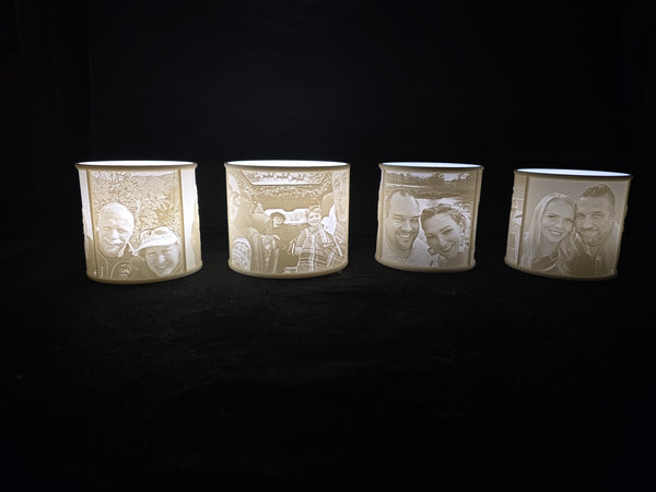 Four cylindrical candles with engraved faces on a black background