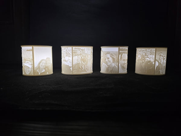 Four cylindrical lanterns with engraved faces on a dark background