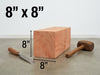 An 8x8x8 inch square wooden block shown on a concrete floor with a chisel and mallet, overlaid with black dimension lines and text reading 8" x 8" and 8".